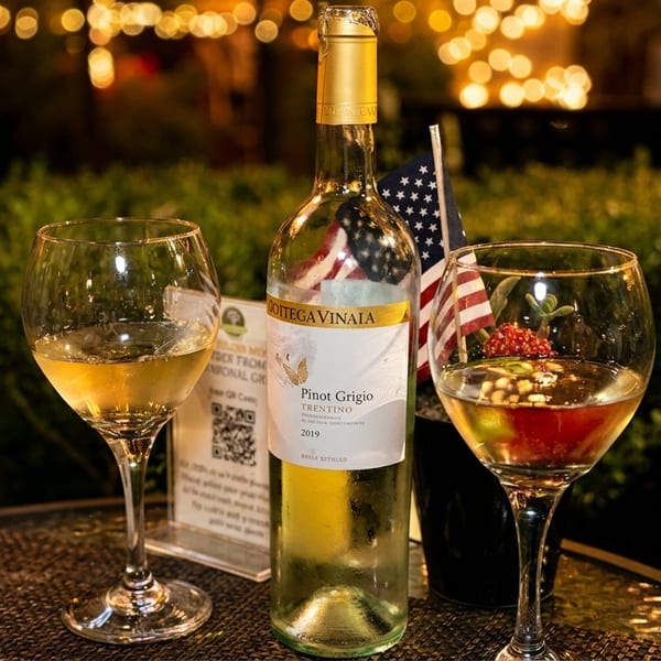 Pinot Grigio wine bottle and two glasses on an outdoor table with an American flag.