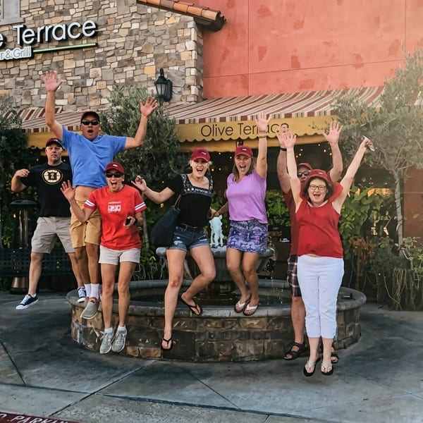 Six excited people jumping in front of the Olive Terrace Bar & Grill entrance.