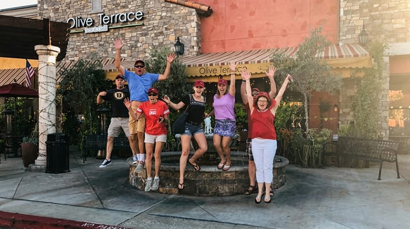 Six excited people jumping in front of the Olive Terrace Bar & Grill entrance.